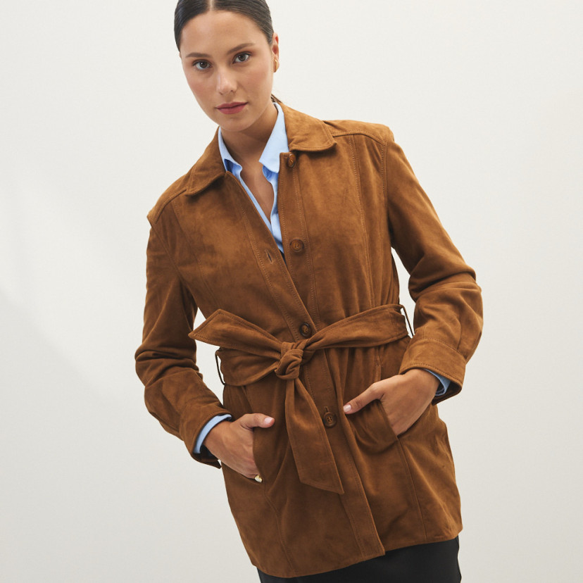 Trench de camurça na cor camelo, vista frontal, modelo com as mãos nos bolsos, plano médio - MONPIEL