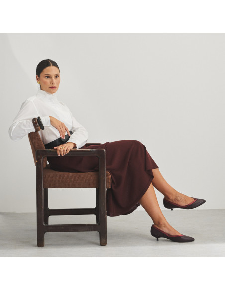 Ballerine à talon Estíbaliz en cuir couleur bordeaux, plan large du modèle assis sur la chaise - MONPIEL