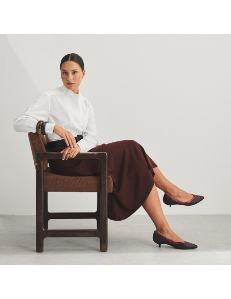 Ballerina Estíbaliz con tacco in pelle color bordeaux, piano generale del modello seduto sulla sedia - MONPIEL