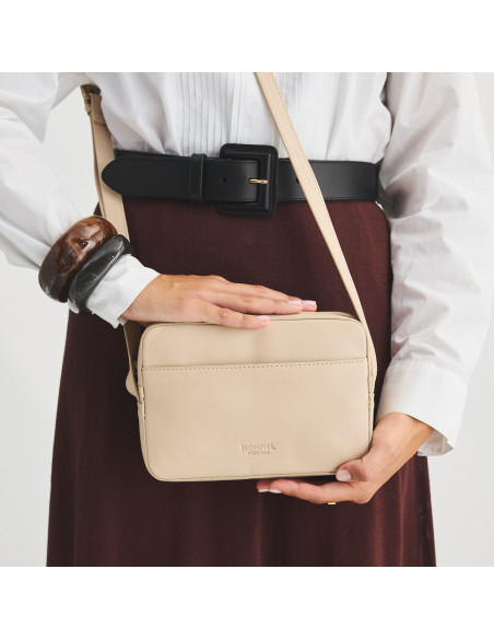 Borsa a tracolla in pelle beige, vista frontale, appesa e tenuta con le mani, dettaglio cintura - MONPIEL