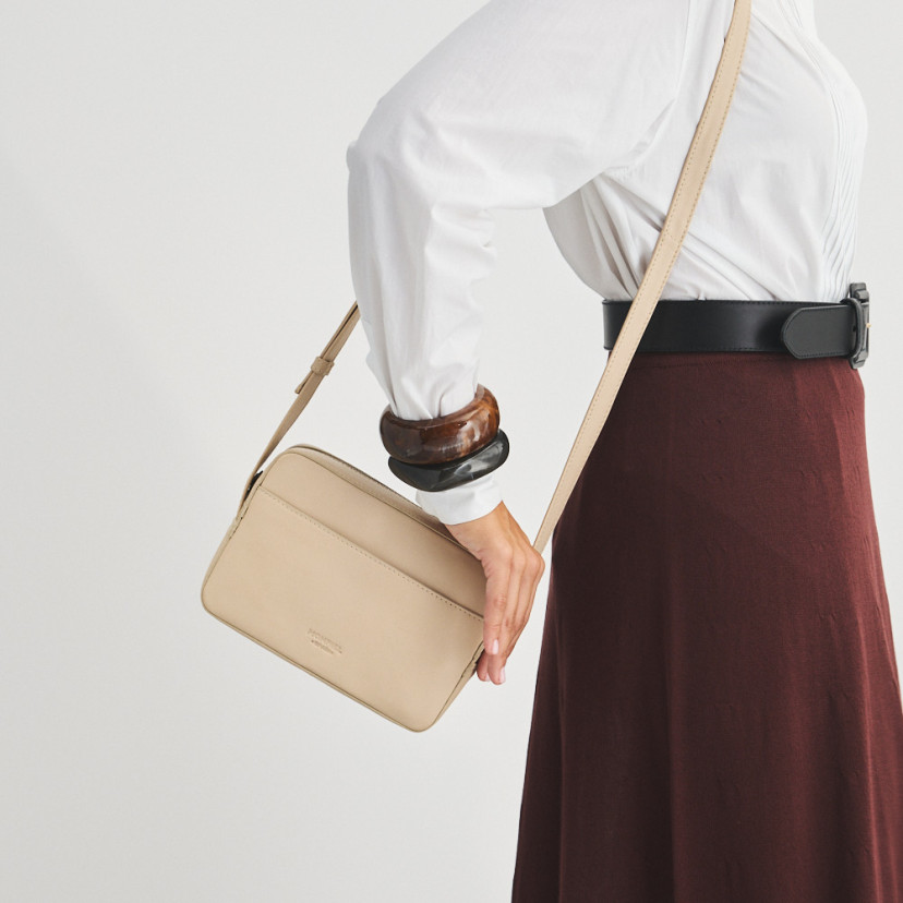 Bolsa a tiracolo de couro bege, pendurada no ombro, em movimento - MONPIEL