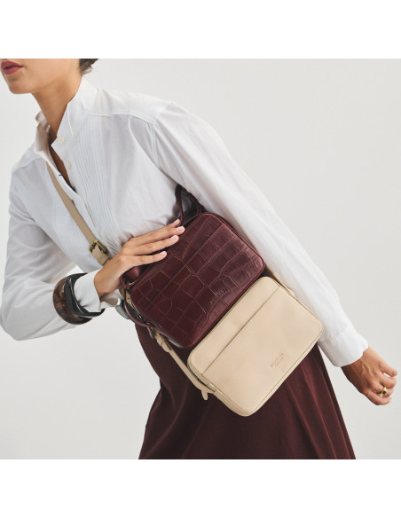 Beige leather crossbody bag alongside burgundy leather crossbody bag with crocodile print, resting - MONPIEL Beige leather crossbody bag alongside burgundy leather crossbody bag with crocodile print, resting - MONPIEL