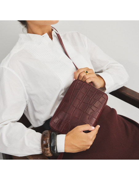 Bolsa a tiracolo de couro bordô com estampa de crocodilo usada como bandoleira e segurada na mão - MONPIEL Bolsa a tiracolo de couro bordô com estampa de crocodilo usada como bandoleira e segurada na mão - MONPIEL