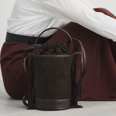 Petit sac seau en cuir noir Roma avec franges, vue de face, posé sur un vase - MONPIEL 2