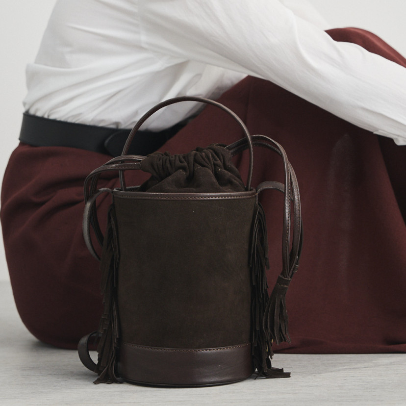 Bolsa bucket de couro com franjas pequena Roma em camurça marrom, vista traseira, apoiada no chão - MONPIEL