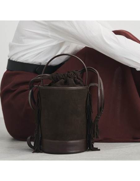 Piccola borsa a secchiello Roma con frange in pelle marrone scamosciata, vista posteriore, appoggiata sul pavimento - MONPIEL