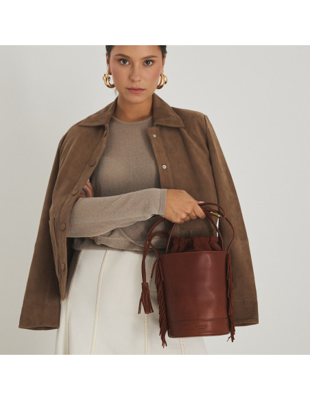 Petit sac seau Roma avec franges en cuir couleur cuir, vue de face, tenu par la poignée courte - MONPIEL