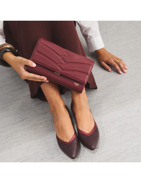Pochette en cuir pour femme Venecia couleur bordeaux, tenue à la main, détail ballerines, gros plan - MONPIEL Pochette en cuir pour femme Venecia couleur bordeaux, tenue à la main, détail ballerines, gros plan - MONPIEL