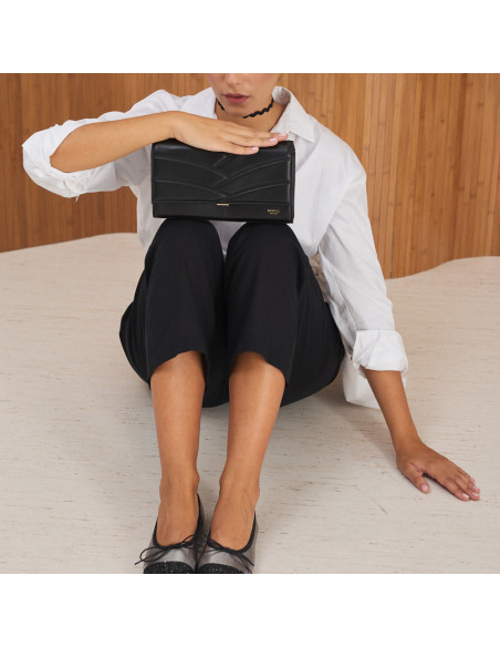 Pochette en cuir pour femme Venecia couleur noire, vue de face, posée sur les genoux - MONPIEL Pochette en cuir pour femme Venecia couleur noire, vue de face, posée sur les genoux - MONPIEL