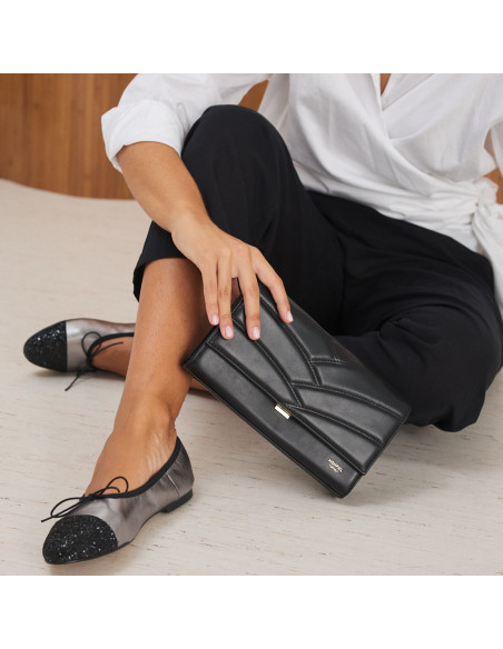 Valeria flat slipper with silver glitter toe, model sitting on the floor with black leather handbag in hand - MONPIEL