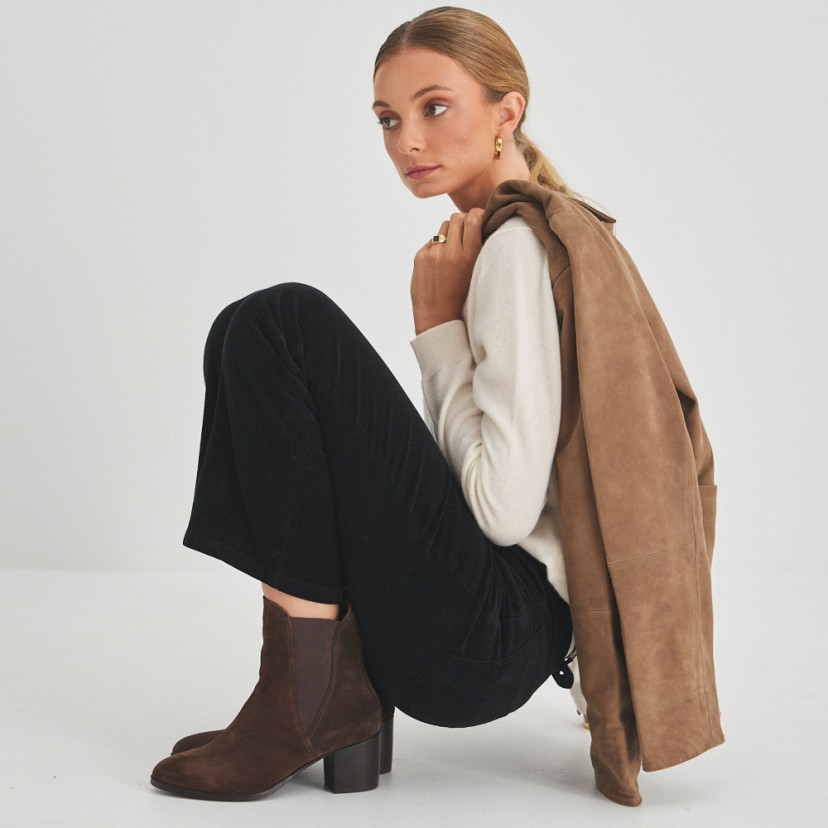 Marcela leather ankle boot in brown suede, side view of model crouching - MONPIEL