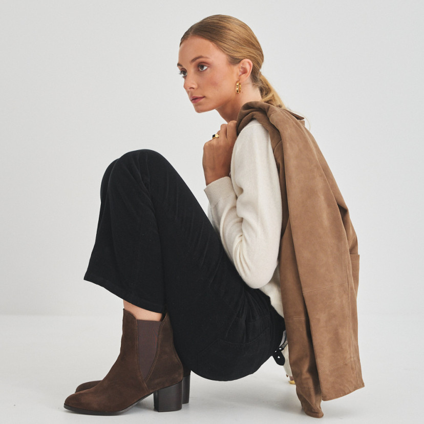 Marcela leather ankle boot in brown suede, side view of model crouching - MONPIEL