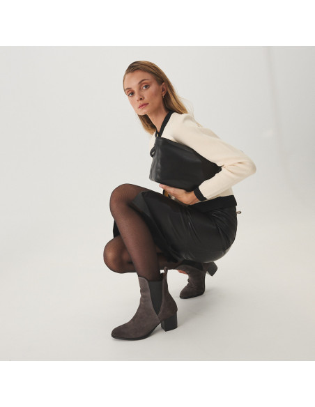 Small black leather knotted bag under the arm, model crouching in profile, wide shot - MONPIEL Small black leather knotted bag under the arm, model crouching in profile, wide shot - MONPIEL