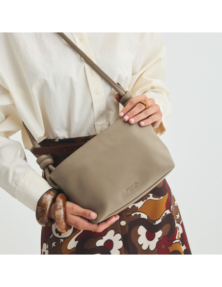 Small taupe leather knotted bag, hanging on the shoulder, held with hands, front view of the bag, tilted, with enlarge - MONPIEL