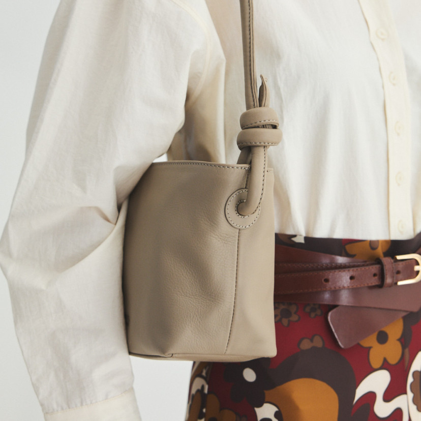 Bolsa de couro com nós pequena na cor taupe pendurada no ombro com alça média e detalhe dos nós - MONPIEL
