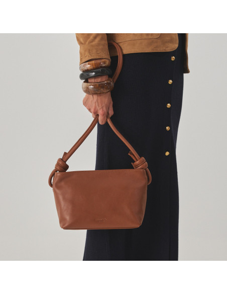 Bolso nudos pequeño de piel en color cuero sujetando asas con la mano y vista del bolso frontal - MONPIEL Bolso nudos pequeño de piel en color cuero sujetando asas con la mano y vista del bolso frontal - MONPIEL