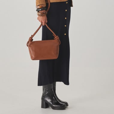 Bolsa pequena de couro com nós na cor taupe, vista frontal e detalhe da alça, apoiada sobre uma rocha - MONPIEL 2