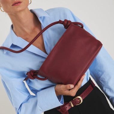 Bolsa pequena de couro com nós na cor taupe, vista frontal e detalhe da alça, apoiada sobre uma rocha - MONPIEL 2