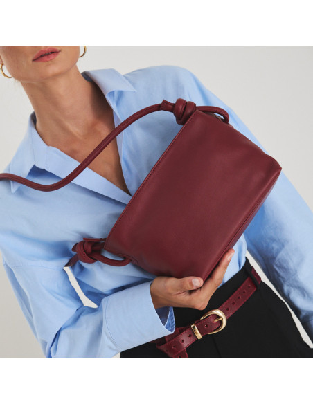 Piccola borsa a nodi in pelle bordeaux, appesa alla spalla, base tenuta con la mano - MONPIEL