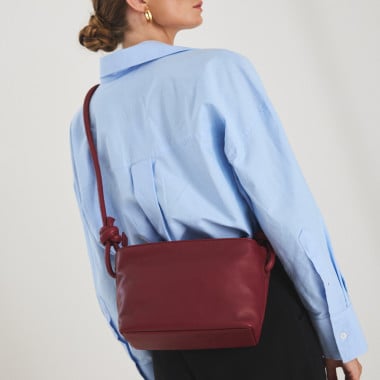 Bolsa pequena de couro com nós na cor taupe, vista frontal e detalhe da alça, apoiada sobre uma rocha - MONPIEL 2