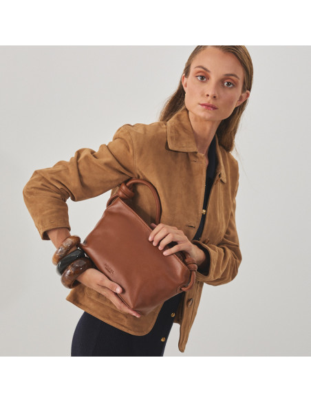 Camel leather jacket for women with stitching details, profile view, holding a leather bag - MONPIEL Camel leather jacket for women with stitching details, profile view, holding a leather bag - MONPIEL
