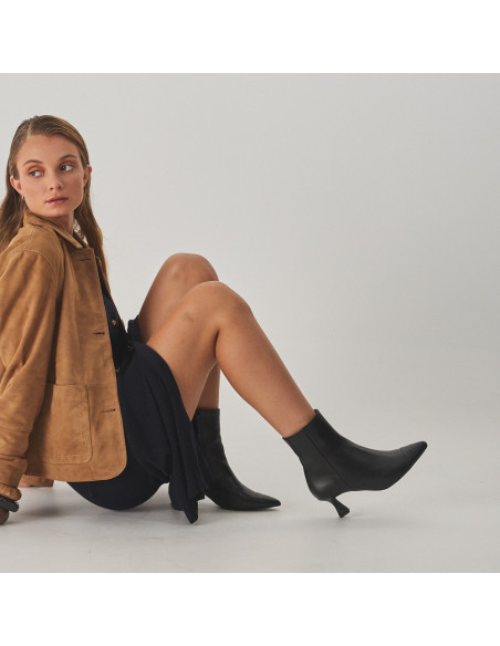 Jimena pointed-toe leather ankle boot in black, side view, full shot of the model sitting on the floor - MONPIEL
