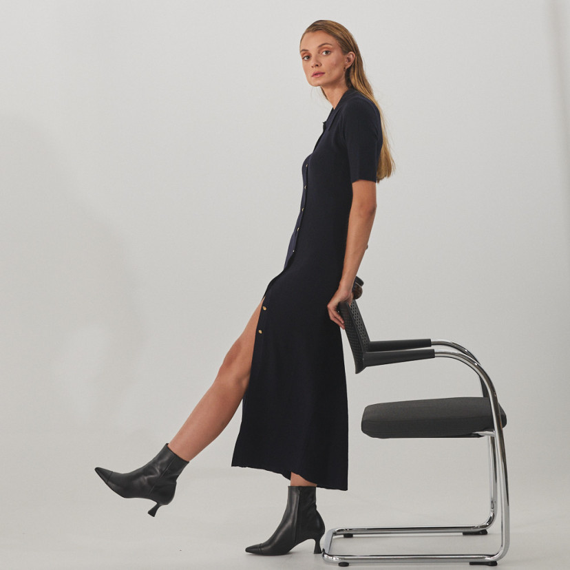 Jimena pointed-toe leather ankle boot in black, side view, full shot of model standing with leg forward, supported by - MONPIEL