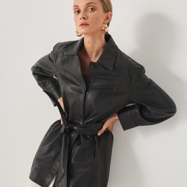 Black leather trench coat, model leaning against the wall, hands on hips - MONPIEL 2