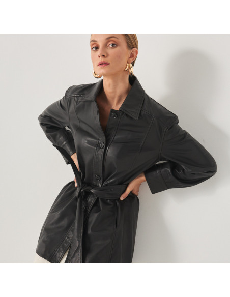 Trench en cuir noir, modèle appuyé contre le mur, mains sur les hanches - MONPIEL Trench en cuir noir, modèle appuyé contre le mur, mains sur les hanches - MONPIEL