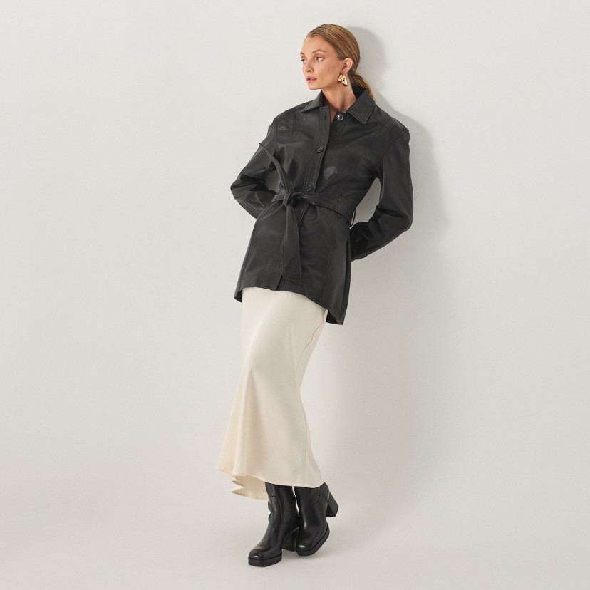 Black leather trench coat with perspective view, full shot of model leaning against the wall - MONPIEL