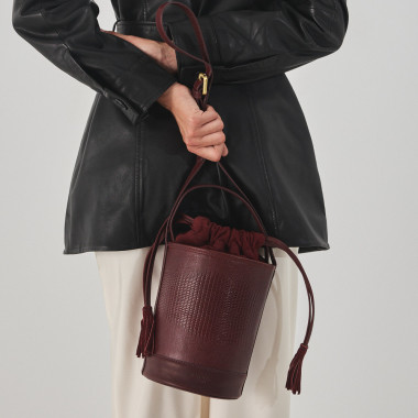 Petit sac seau rond en cuir noir, vue de face, posé sur un livre - MONPIEL 2