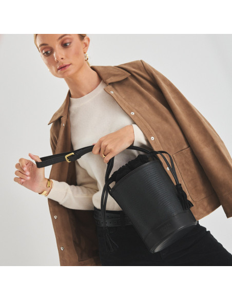 Small round bucket leather bag in black snake print, front view, jacket draped over the shoulders - MONPIEL