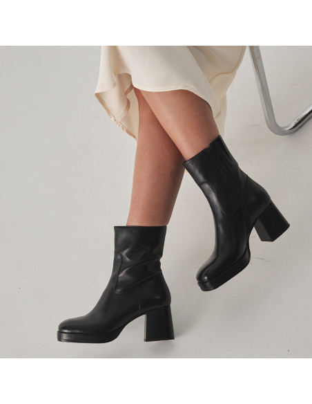 Botín de plataforma claudia en color negro con vista de perfil, piernas cruzadas en primer plano - MONPIEL Botín de plataforma claudia en color negro con vista de perfil, piernas cruzadas en primer plano - MONPIEL