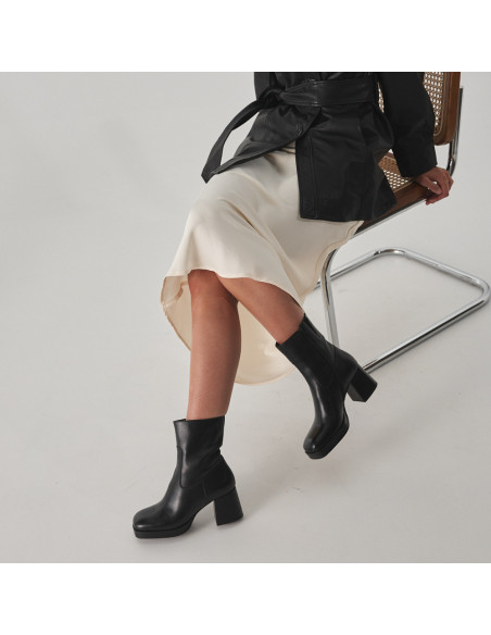 Botín de plataforma claudia en color negro con vista en perspectiva, piernas cruzadas, plano medio - MONPIEL Botín de plataforma claudia en color negro con vista en perspectiva, piernas cruzadas, plano medio - MONPIEL