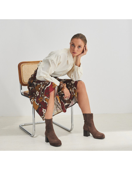 Claudia platform boot in brown suede with printed skirt, perspective view, full shot of the model sitting on the chair - MONPIEL Claudia platform boot in brown suede with printed skirt, perspective view, full shot of the model sitting on the chair - MONPIEL