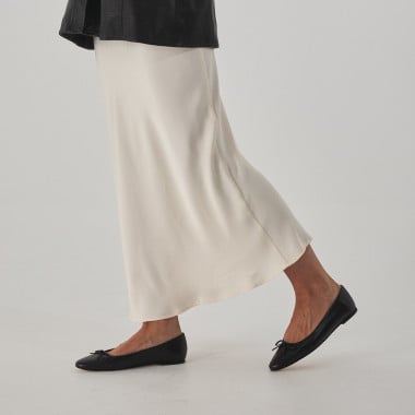 Manolita pointed-toe ballerina in black with perspective view, resting on a stone in close-up - MONPIEL 2