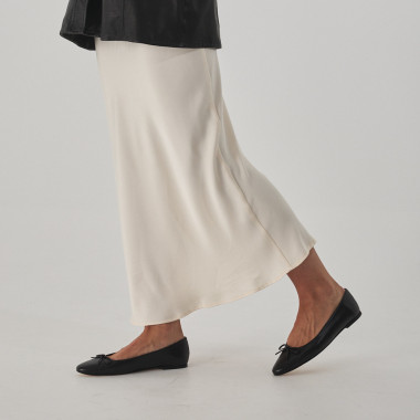 Black Manolita ballet flat with stylized toe, perspective view, resting on a stone, close-up - MONPIEL 2