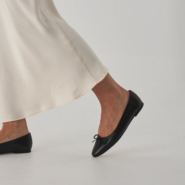 Manolita pointed-toe ballerina in black with perspective view, resting on a stone in close-up - MONPIEL 2