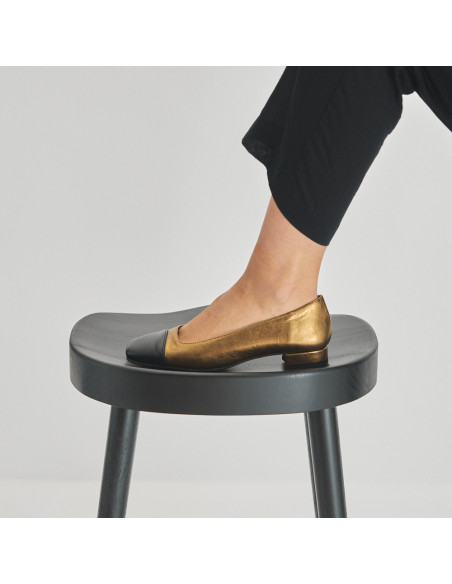 Sapato feminino com ponta quadrada de couro em cor ocre e bico preto, pé apoiado sobre o banquinho com vista de perfil - MONPIEL Sapato feminino com ponta quadrada de couro em cor ocre e bico preto, pé apoiado sobre o banquinho com vista de perfil - MONPIEL