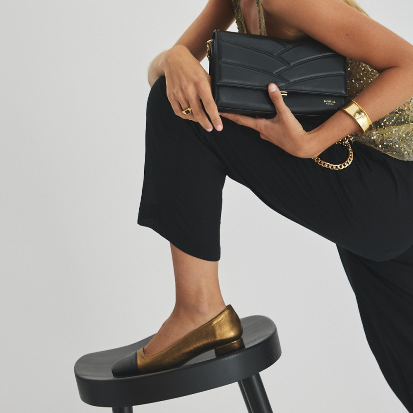 Sapato feminino com ponta quadrada de couro em cor ocre e bico preto, pé apoiado sobre o banquinho de perfil, com bols - MONPIEL