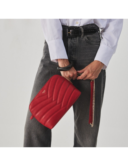 Borsa imbottita in pelle con catena dorata di colore rosso, catena tenuta nelle mani e borsa inclinata, primo piano - MONPIEL Borsa imbottita in pelle con catena dorata di colore rosso, catena tenuta nelle mani e borsa inclinata, primo piano - MONPIEL