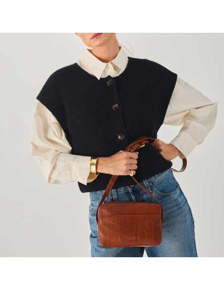 Bolsa de couro croco na cor couro com alça segurada na mão, vista frontal e plano médio modelo - MONPIEL Bolsa de couro croco na cor couro com alça segurada na mão, vista frontal e plano médio modelo - MONPIEL