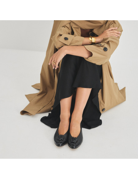 Ameliè patent leather ballerina with floral toe in black, front view, knees bent, model sitting on the floor - MONPIEL