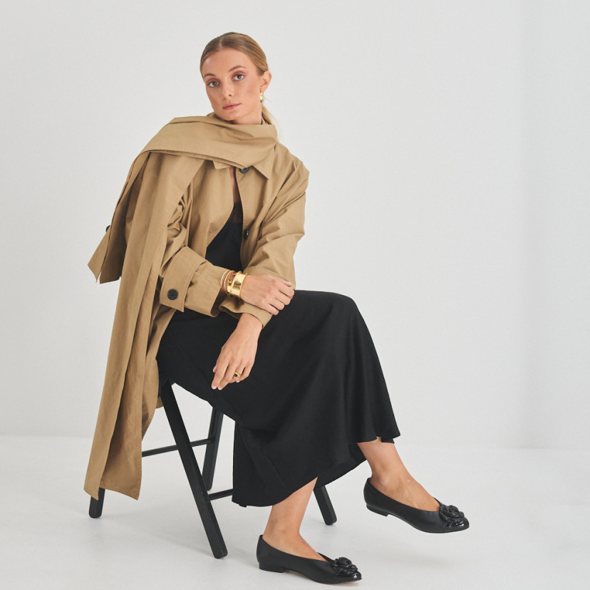 Ameliè patent leather ballerina with flower toe in black, perspective view, full shot of model sitting on the chair - MONPIEL