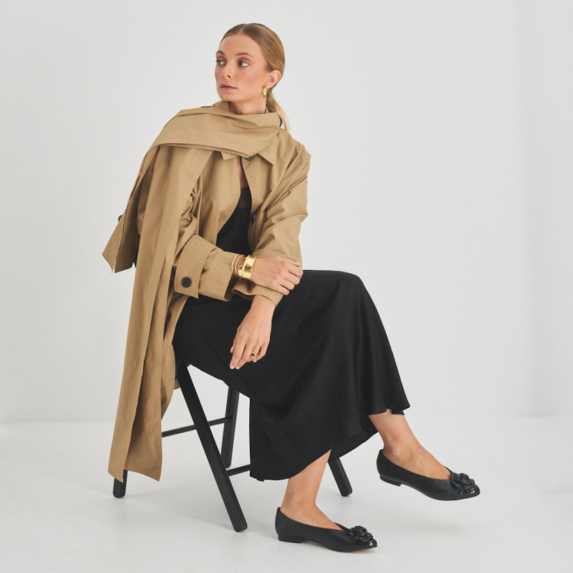 Ameliè patent leather ballerina with flower toe in black, perspective view, full shot of model sitting on the chair - MONPIEL