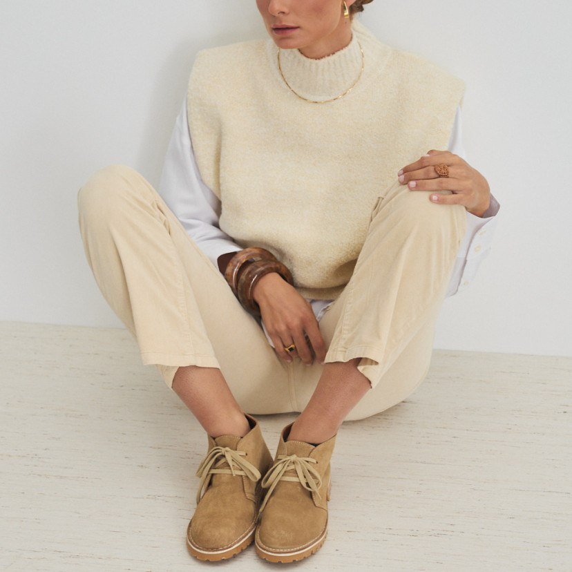 Bota de couro Heidi em cor areia, vista frontal, modelo sentada encostada na parede - MONPIEL