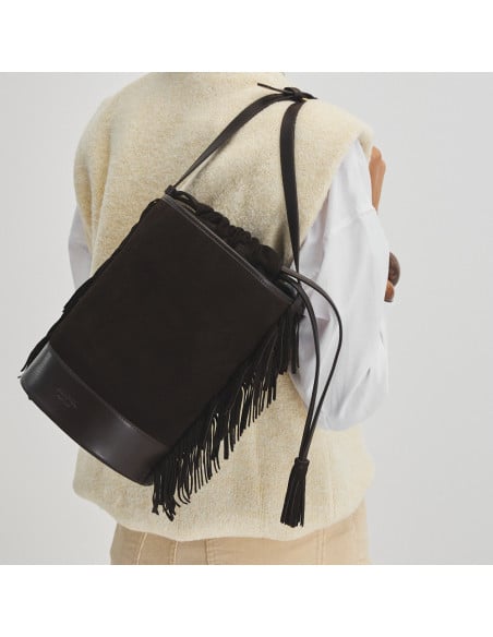 Bolsa bucket grande em camurça marrom com franjas, pendurada nas costas, vista frontal - MONPIEL