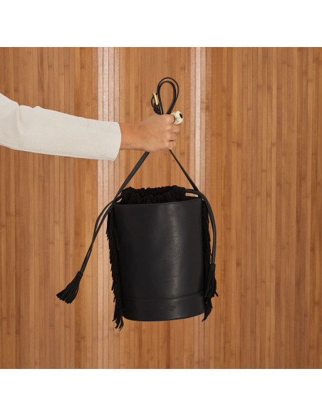 Bolso de cubo de piel con flecos grande roma en color negro cogido de la mano colgando con vista frontal - MONPIEL