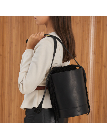 Bolsa bucket grande em couro preto com franjas, pendurada nas costas, plano médio - MONPIEL