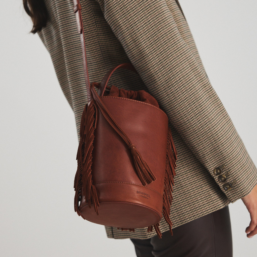 Leather bucket bag with large blunt fringes in tan leather shoulder strap in close-up - MONPIEL